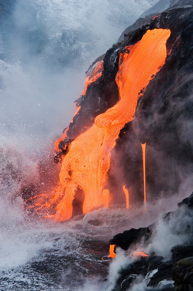 Hawaii, Big Island, near Kalapana, Pahoehoe lava flowing from Kilauea into Pacific Ocean, Seaspray and steam in air.