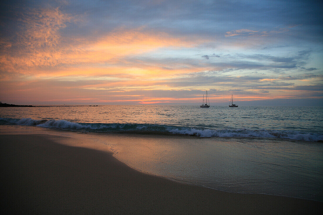 Hawaii, Big Island, Kaunaoa Beach at Sunset, sailboats rest on the calm ocean.