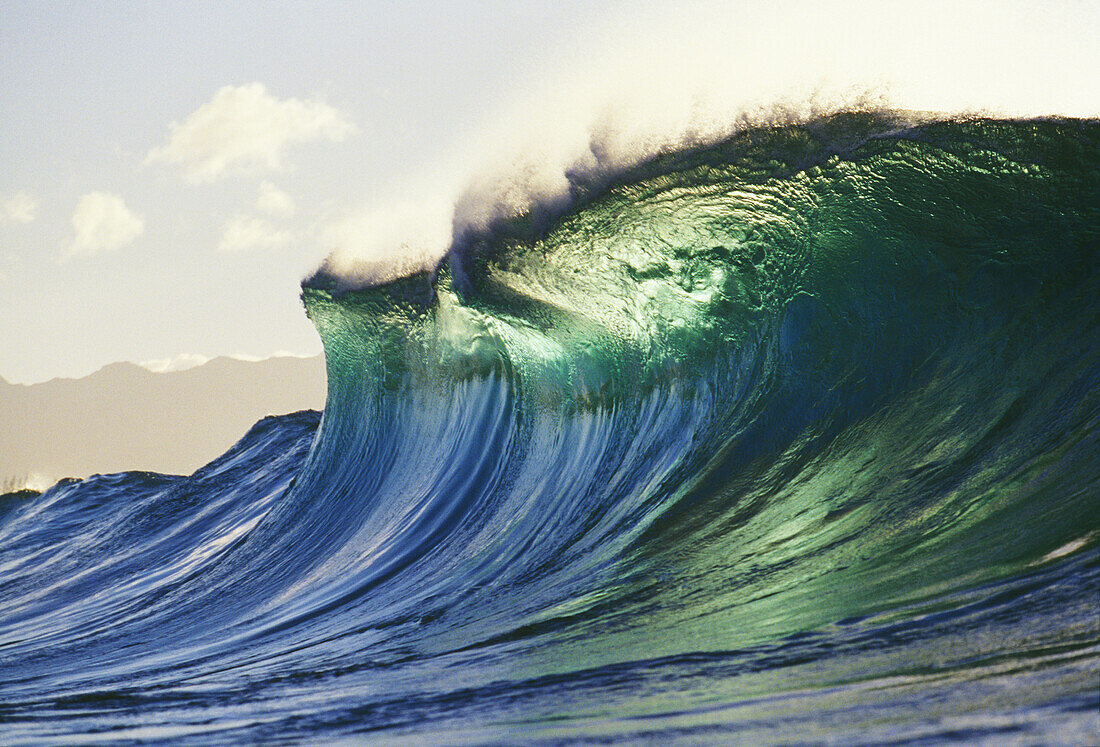 ''Hawaii, Oahu, North Shore; large green blue wave about to curl, mountains in background.''