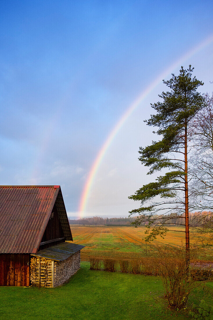 Rural scene, a rainbow in the sky, after rain., Rainbow over a shed or barn