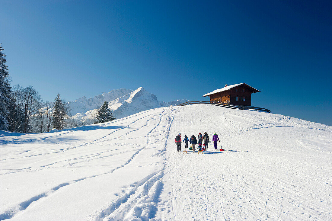 People sledging at Eckbauer, Alpspitze in the background, Garmisch-Partenkirchen, Bavaria, Germany