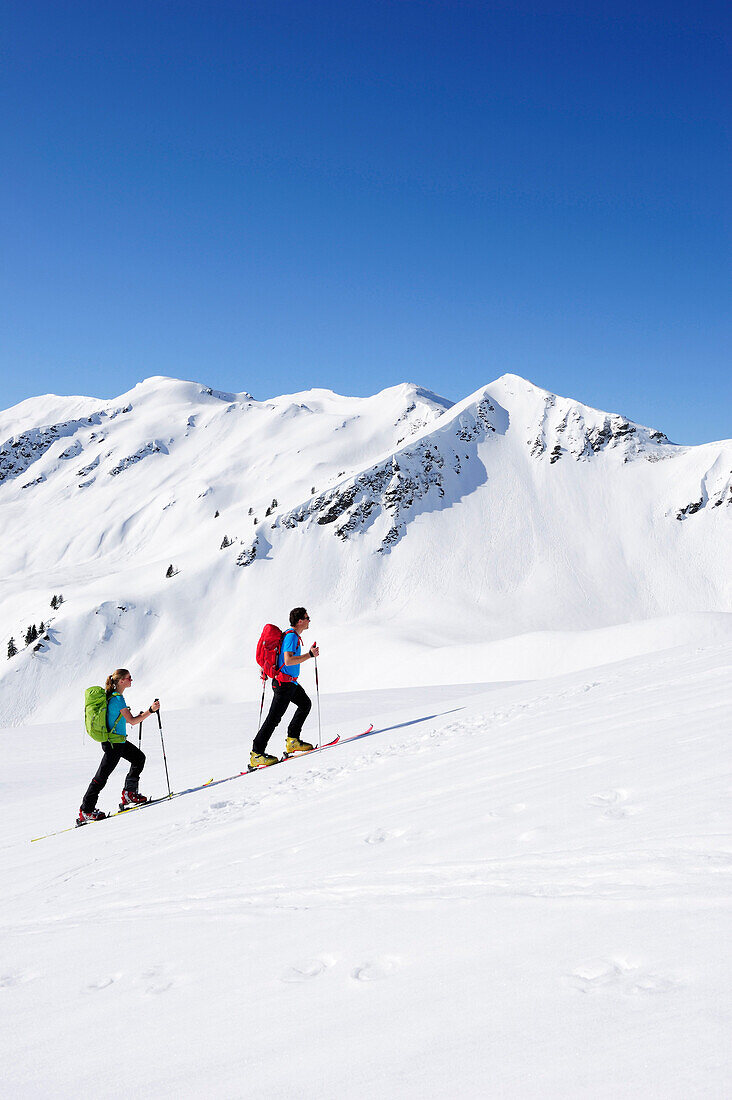 Zwei Skitourengeher beim Aufstieg zum Brechhorn, Großer Rettenstein im Hintergrund, Kitzbüheler Alpen, Tirol, Österreich