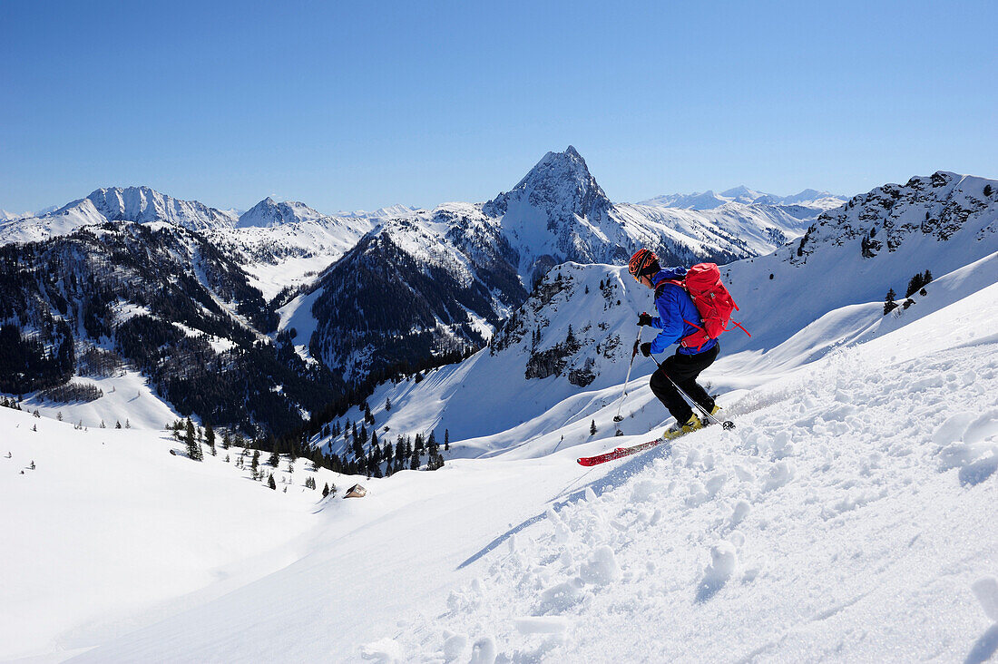 Junger Mann auf Skitour fährt vom Brechhorn ab, Großer Rettenstein im Hintergrund, Kitzbüheler Alpen, Tirol, Österreich
