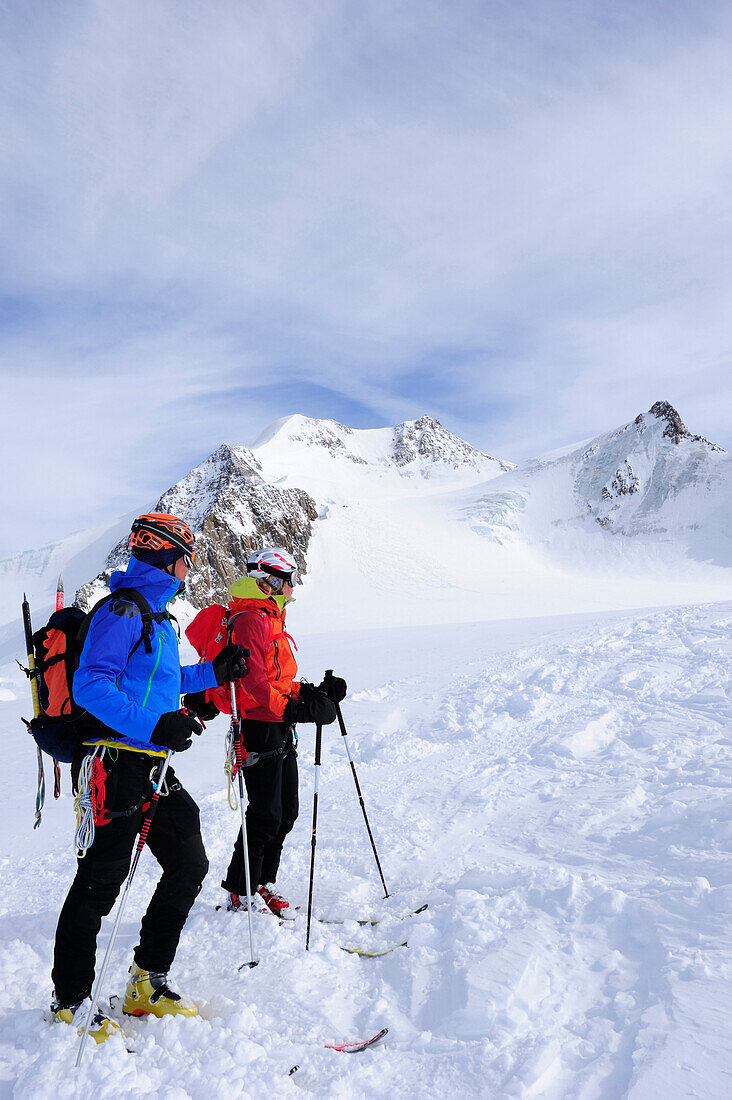 Young woman and young man downhill skiing from Wildspitze on glacier, Oetztal Alps, Tyrol, Austria