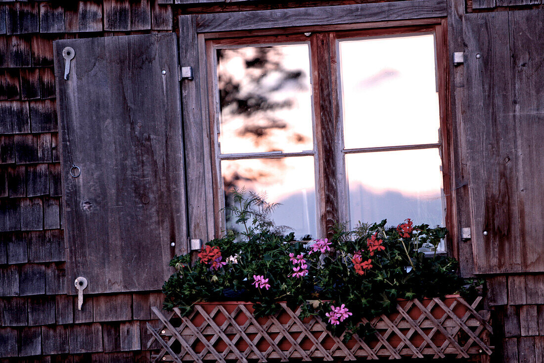 Fenster einer Hütte in den Bergen bei Sonnenuntergang, Oberberg, Bayern, Deutschland