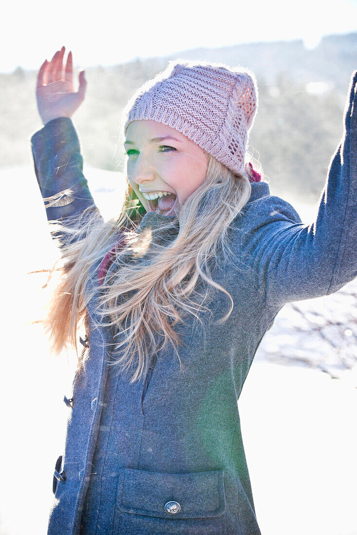 Junge Frau steht lachend im Schnee, Steiermark, Österreich