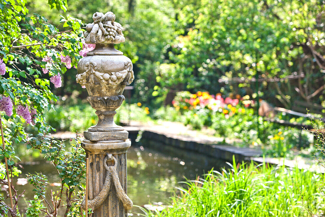 Sculpture with blossoming lilac and a pond in the background, Vienna, Austria