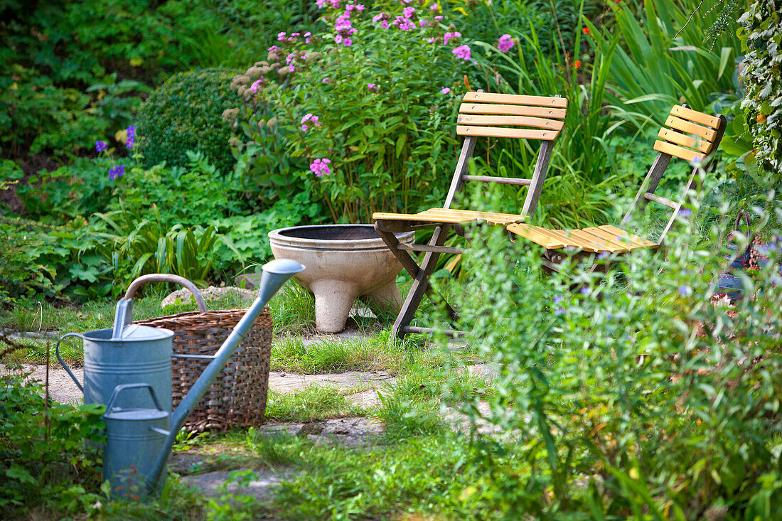 Gießkanne mit Korb und zwei Stühle, Garten im Sommer, Wien, Österreich