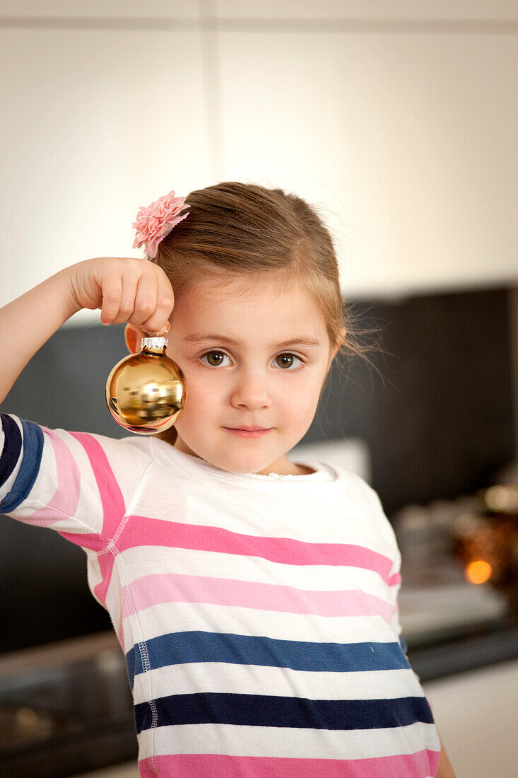 Mädchen (4 Jahre) hält eine Christbaumkugel, Steiermark, Österreich