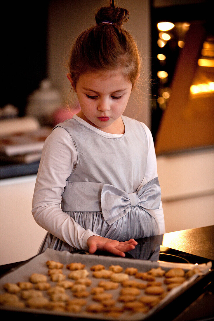 Girl (4 years) looking at a baking sheet with Christmas cookies