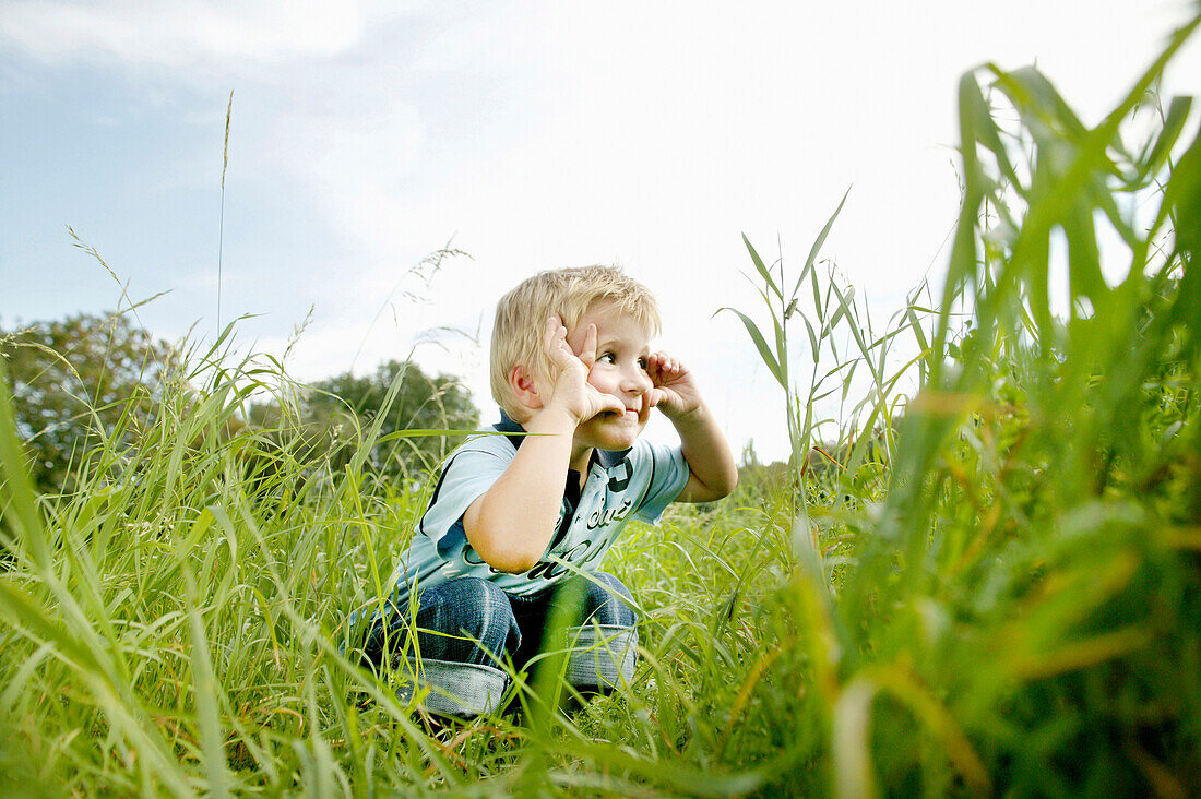 Junge (3 Jahre) hockt im Gras, Wien, Österreich