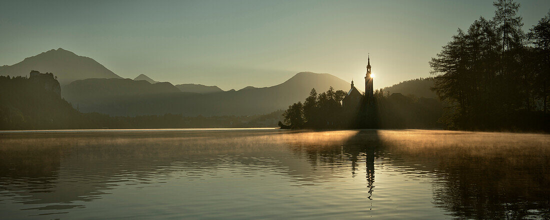 Blick im Morgenlicht auf Marienkirche auf Insel im See von Bled, Nebel, Wasserdampf, Julische Alpen, Gorenjska, Slowenien