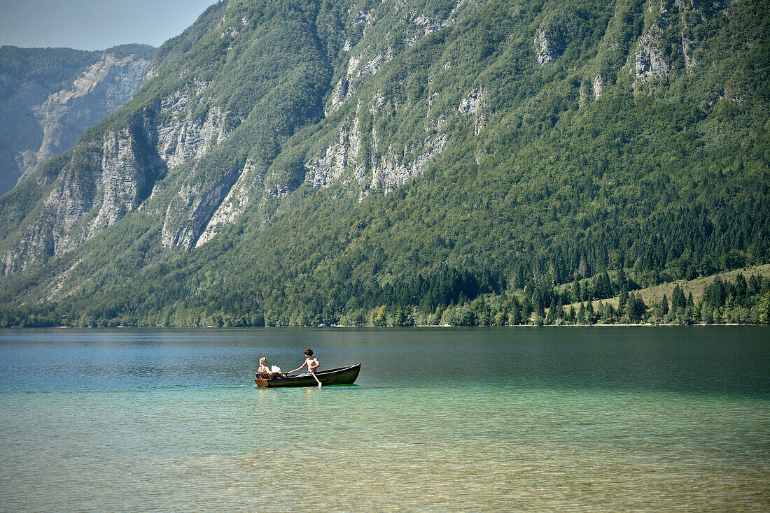 Mann, Frau und Hund paddeln mit Boot im See von Bohinj, Triglav Nationalpark, Julische Alpen, Gorenjska, Slowenien