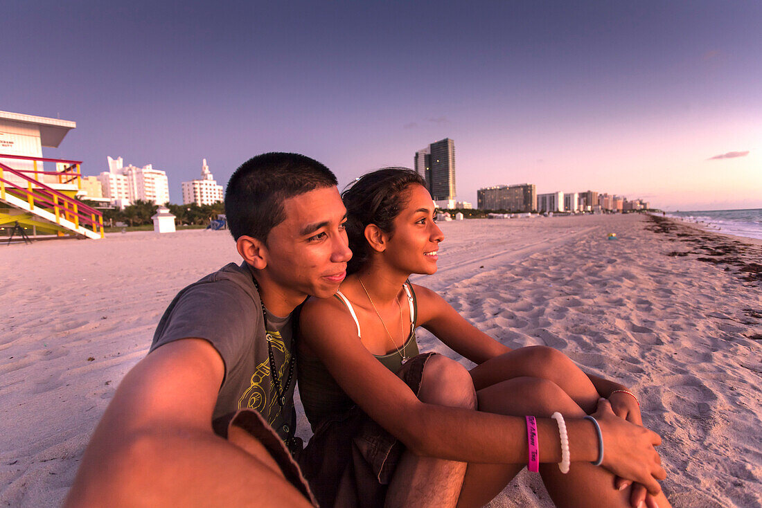 Young latino couple watching the sunrise on the beach, South Beach, Miami, Florida, USA