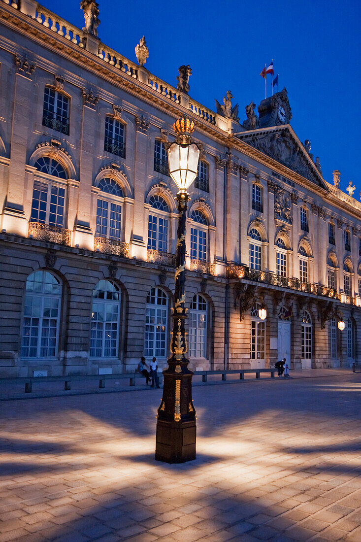 Gilded wrought iron lantern, created by Jean Lamou in front of the Hotel de Ville (City Hall) on Place Stanislas at night, Nancy, France