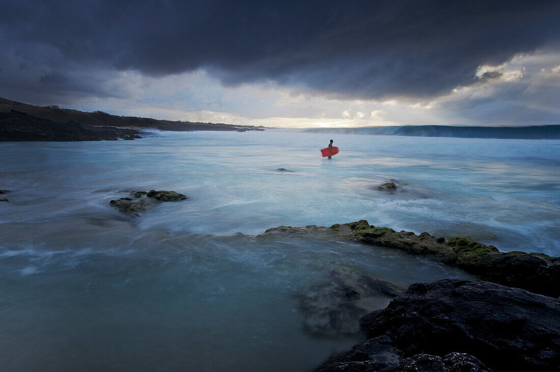 Hawaii, Big Island, Kona Coast, Kua Bay, Bodyboarder checking out stormy surf, Long exposure - showing motion.