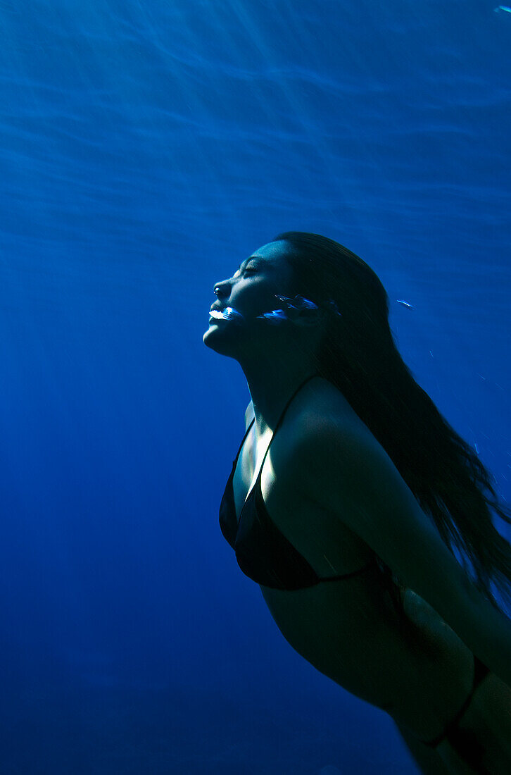 Hawaii, Big Island, Honaunau Bay, Young woman exhales as she swims to the surface.