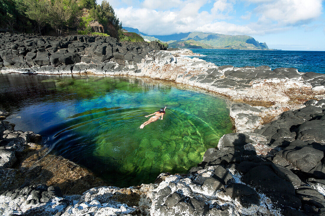 Hawaii, Kauai, Princeville, Queens Bath, Woman snorkeling in saltwater pool.