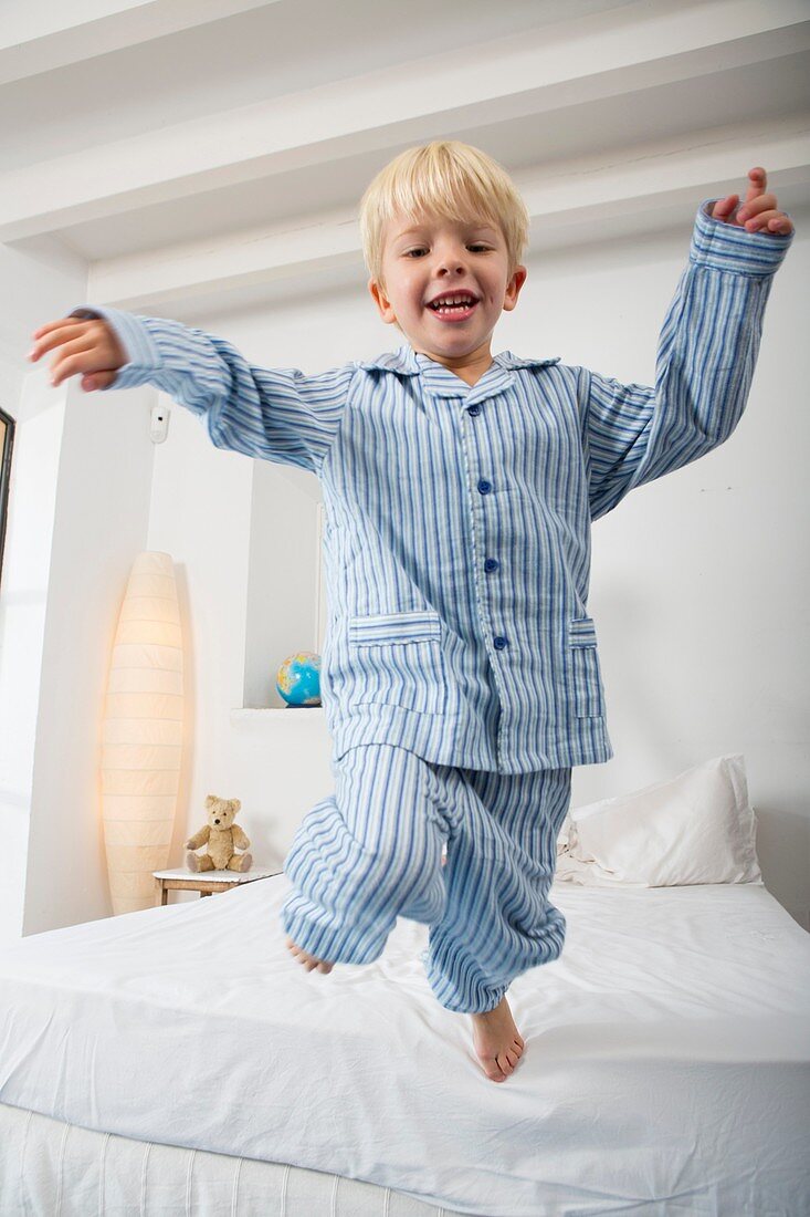 Four year old boy jumping off the bed