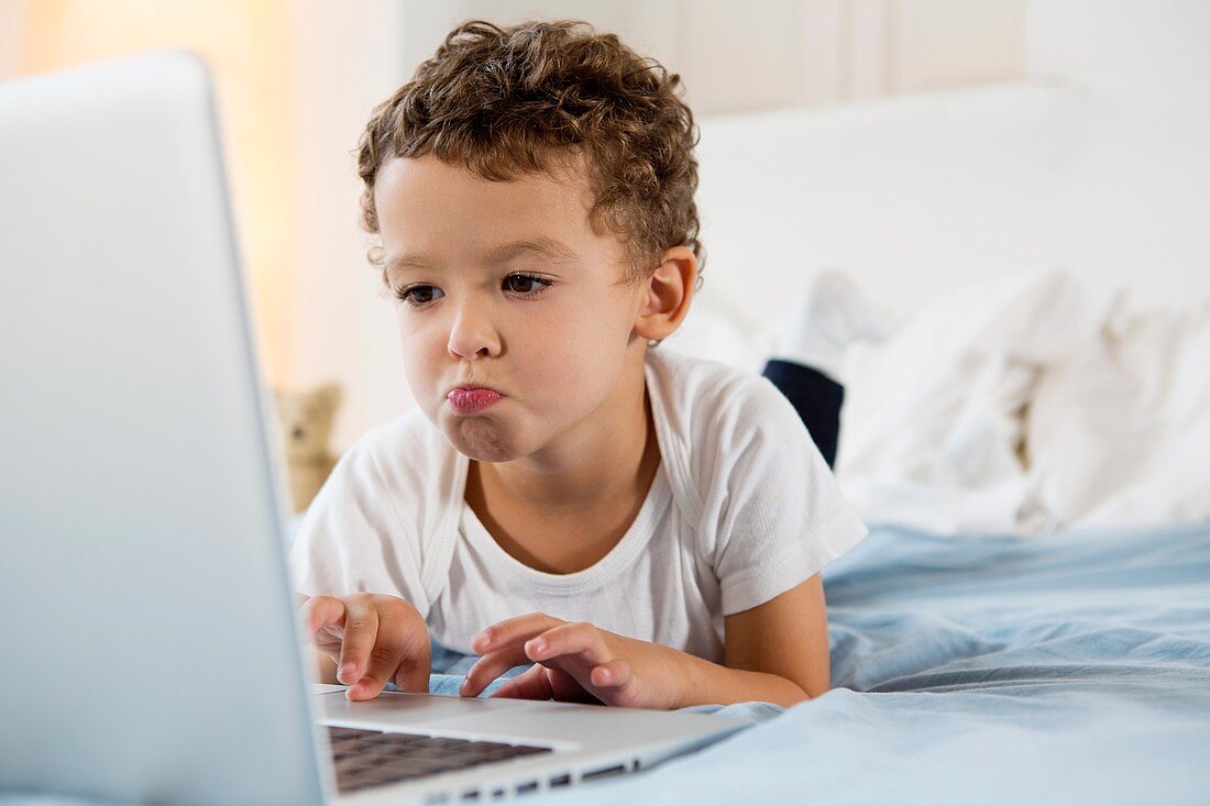 Four year old boy playing games on a laptop