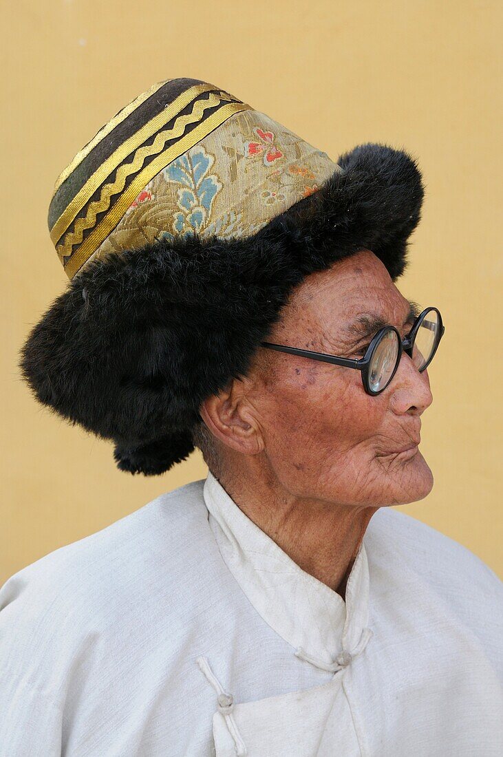 China, Qinghai, Amdo, Tongren Rebkong, Monastery of Gomar Guomari Si, Losar New Year festival, Tibetan elder wearing the traditional fur hat