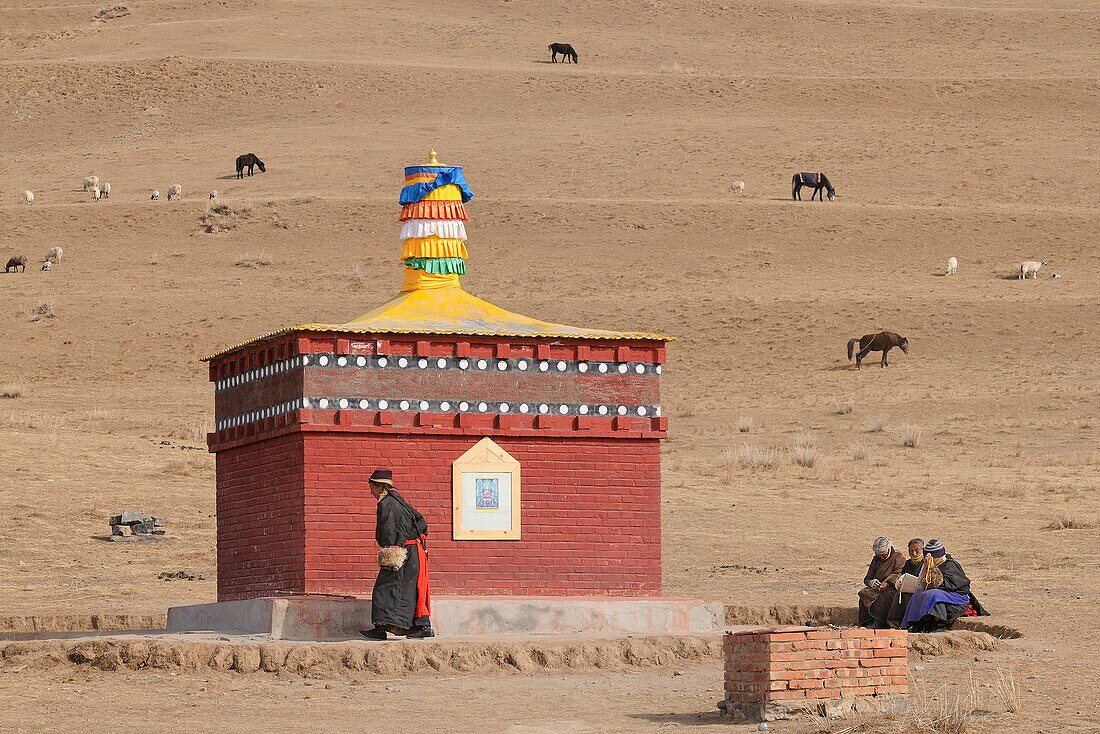 China, Gansu, Amdo, Xiahe region, Old woman doing a kora circumambulation around a lonely chorten
