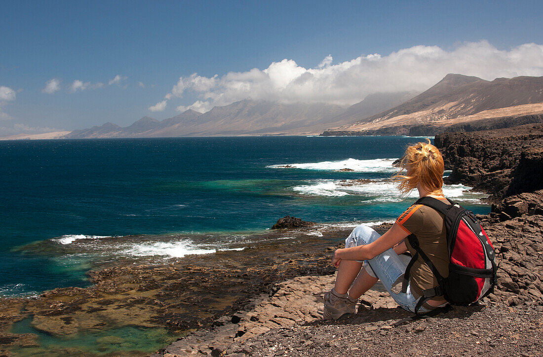 Frau beim wandern sitzt auf Felsen, National Park, Jandia, Fuerteventura, Kanarische Inseln, Spanien, Europa
