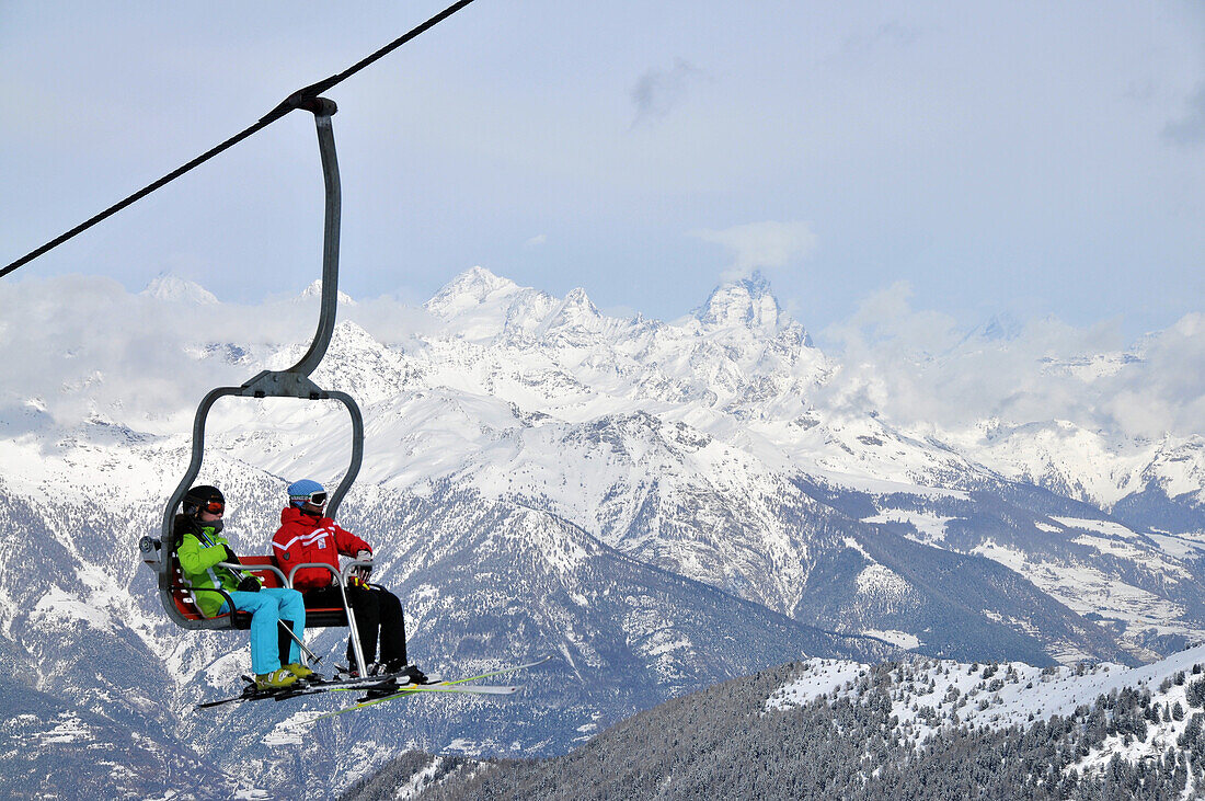 Two people in a ski lift, Pila ski resort, Aosta with Matterhorn, Aosta Valley, Italy