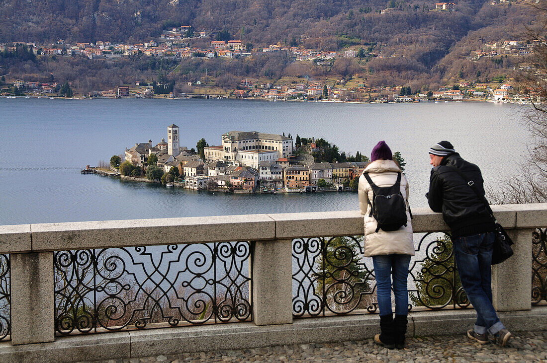 Couple looking towards the Island of San Giulio, Lago d'Orta, Piedmont, Italy