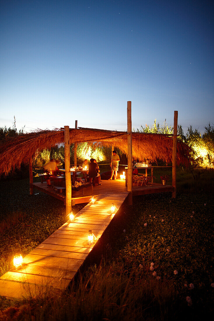 Gäste grillen auf der Holzterrasse am Abend mit Öllampen, Hotel Areias do Seixo, Povoa de Penafirme, A-dos-Cunhados, Costa de Prata, Portugal