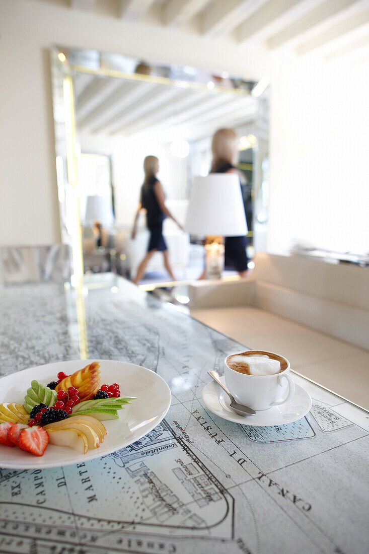 A cup of coffee and a plate with fruits on a tabel in a hotel suite, Venice, Veneto, Italy