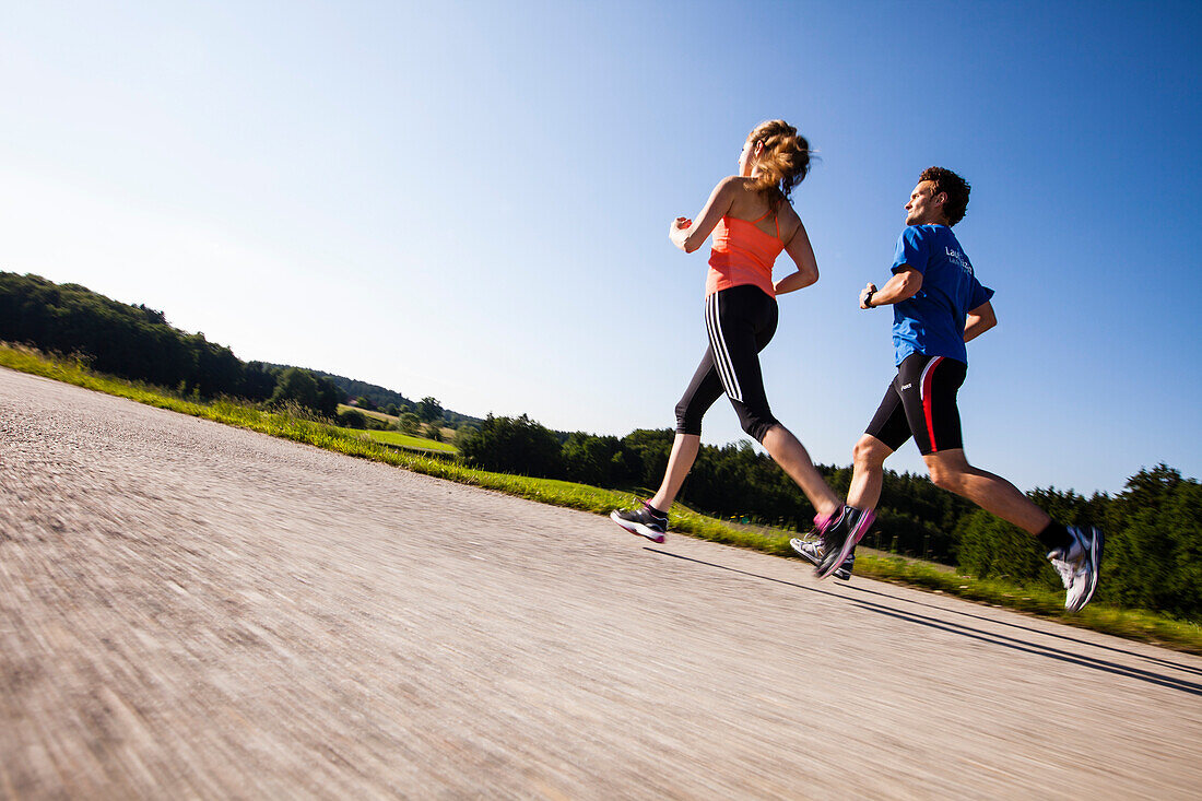 Two people jogging along a road, Upper Bavaria, Germany