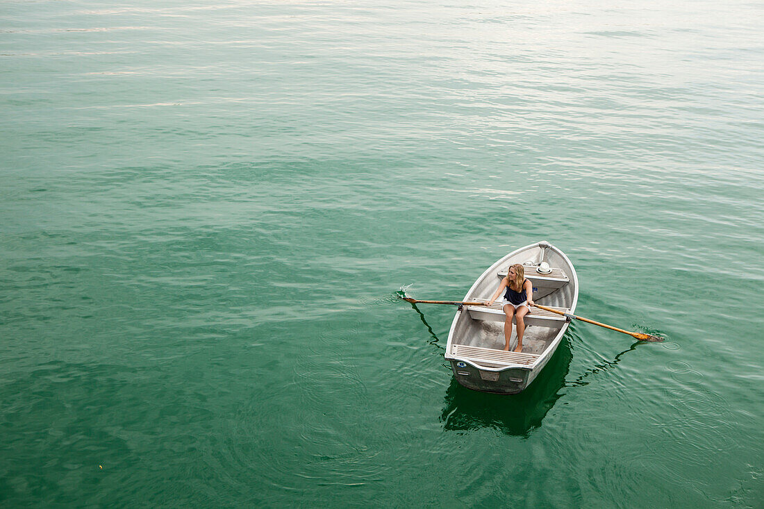 Junge Frau in einem Ruderboot auf dem Starnberger See, Bayern, Deutschland