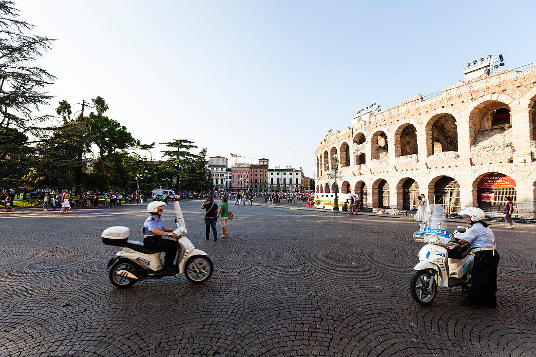 Two police officers with motor scooters, Verona Arena in background, Verona, Veneto, Italy