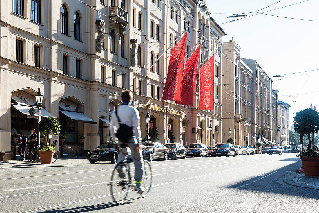 Cyclist riding along street Maximilianstrasse near Hotel Vier Jahreszeiten, Munich, Bavaria, Germany