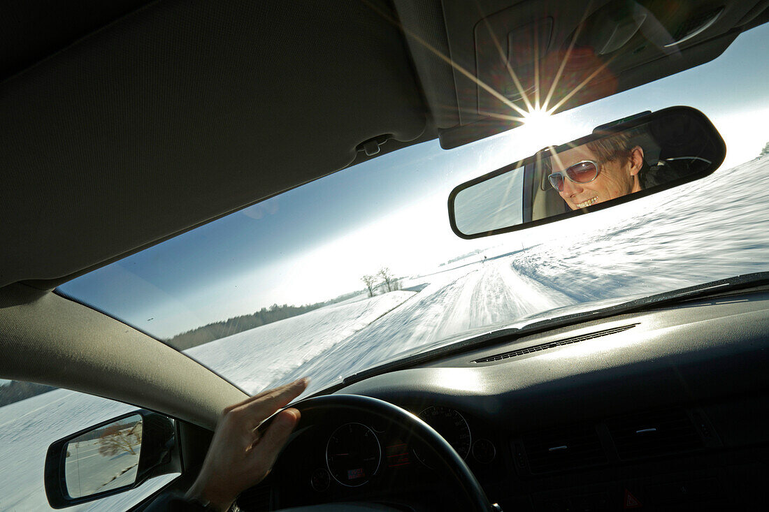 Man driving a car along a snow-covered street, Bavaria, Germany