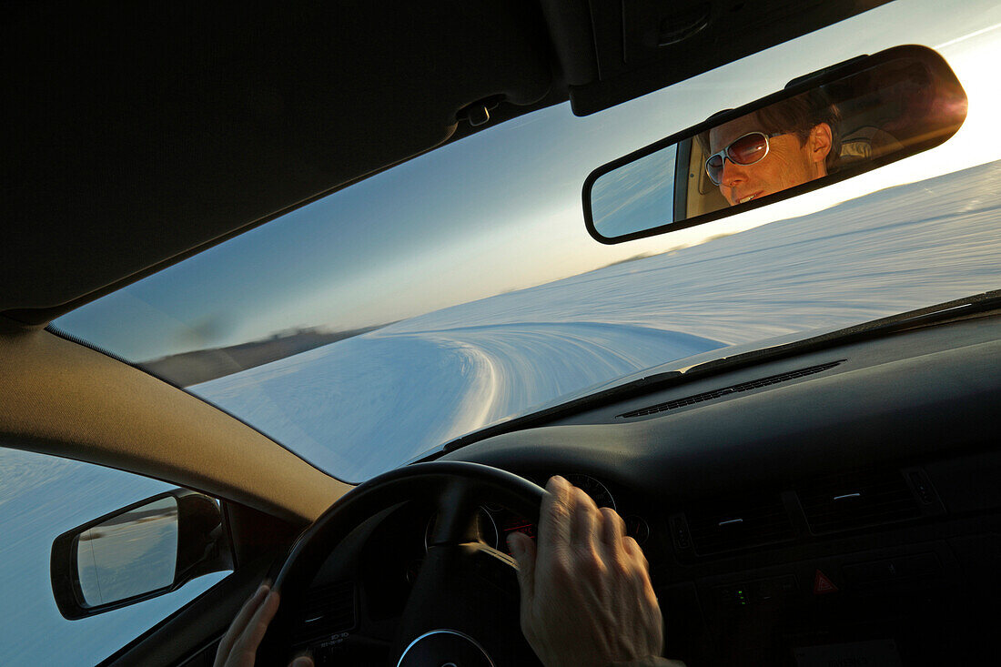 Man driving a car along a snow-covered street, Bavaria, Germany