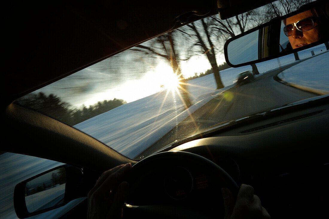 Man driving a car along a street in winter, Bavaria, Germany