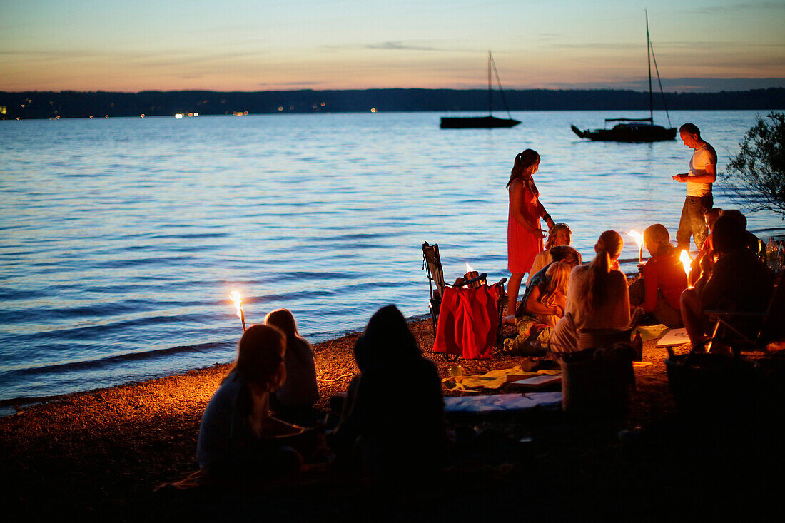 Erwachsene und Kinder mit Fackeln am Seeufer, Starnberger See, Bayern, Deutschland
