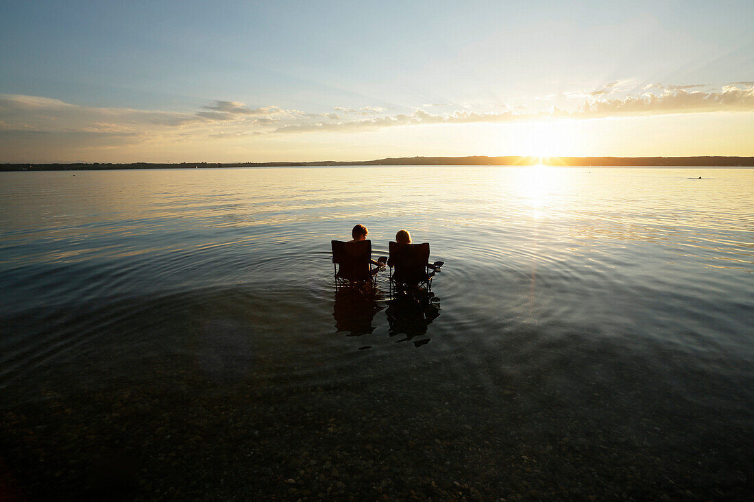 Two boys sitting in folding chairs in lake Starnberg, Bavaria, Germany