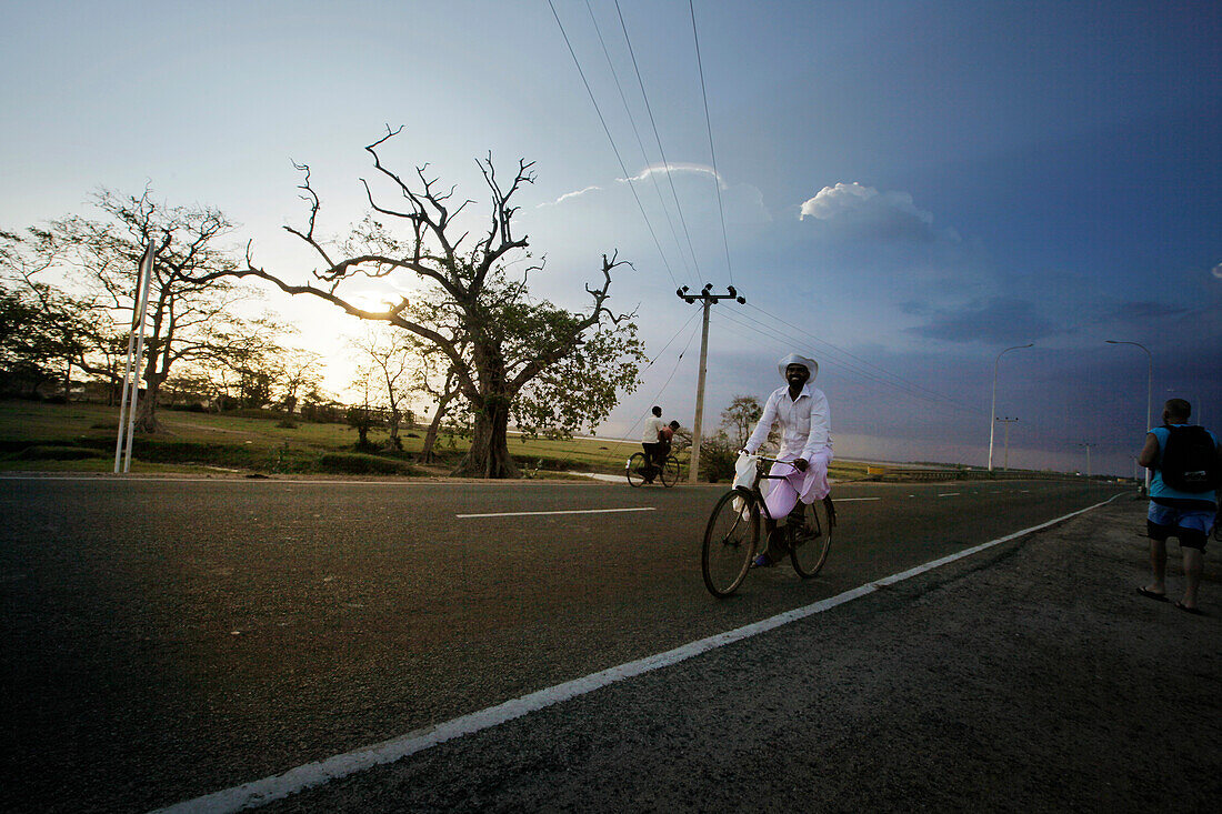 Cyclists passing a street, Arugam Bay, Ampara District, Sri Lanka