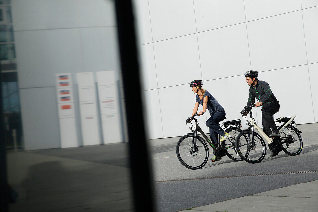 Couple riding e-bikes, Munich, Bavaria, Germany