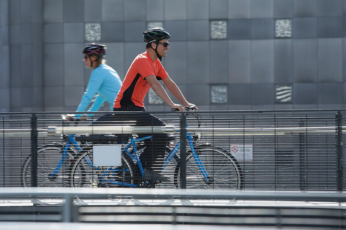 E-bike riders passing a bridge, Munich, Bavaria, Germany