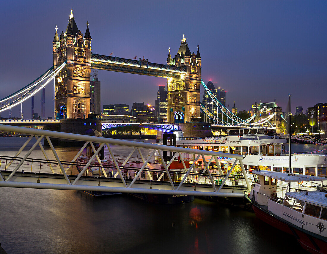 Tower Bridge with excursion boat at night, London, England