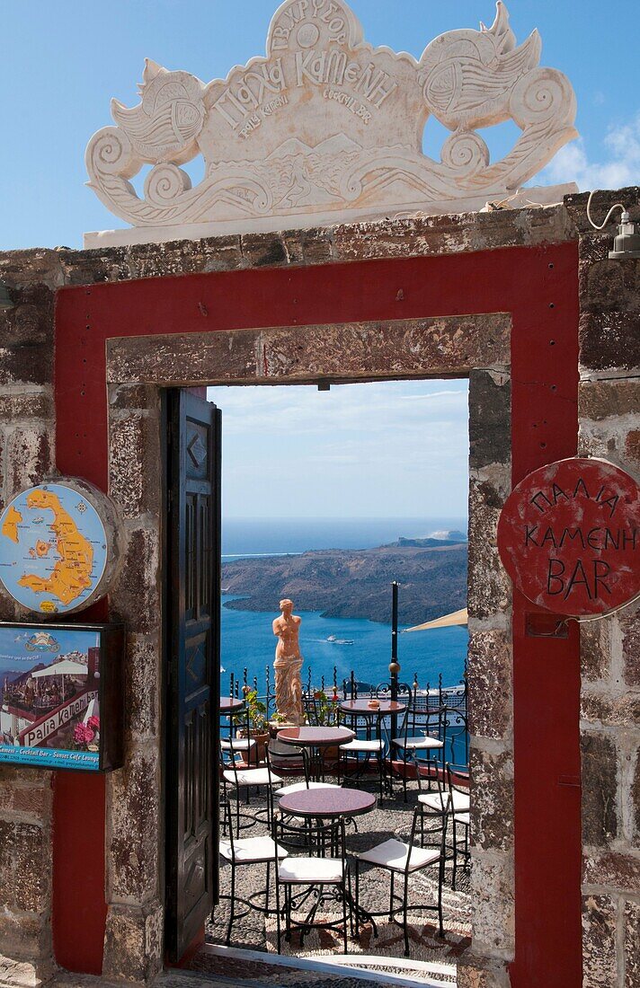 Looking down through doorway at romantic restaurant and the sea with statue in Santorini Greece in Greek Islands