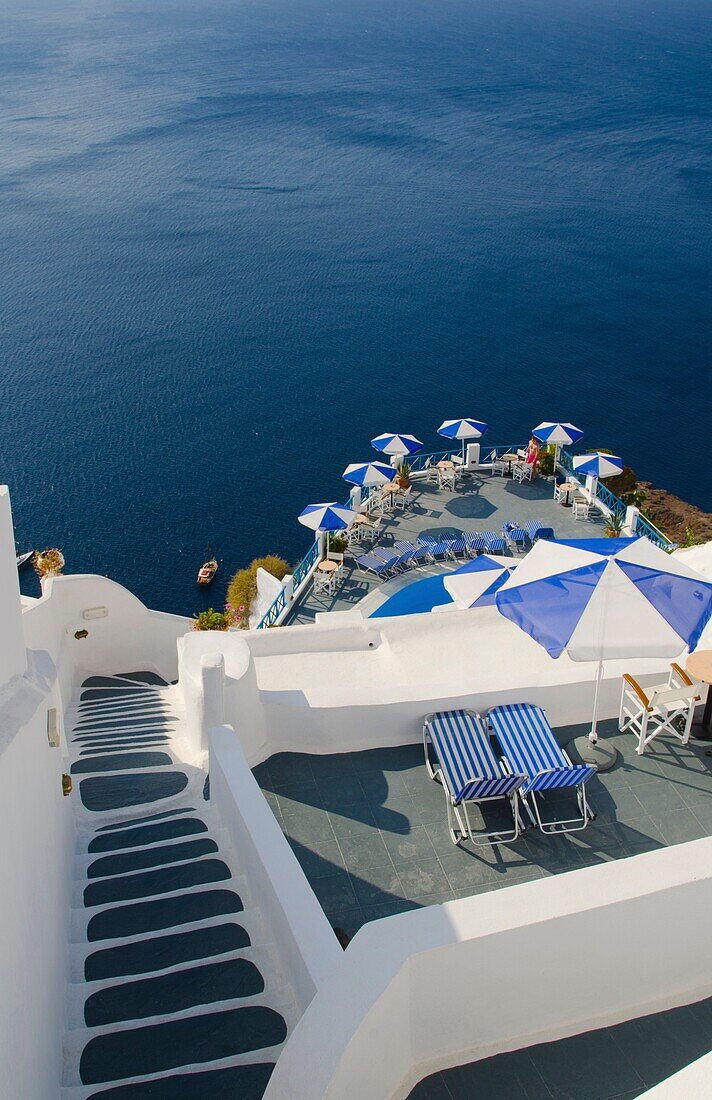 Looking down mountain stairs onto balcony with umbrella in Fira in Santorini Greece in Greek Islands