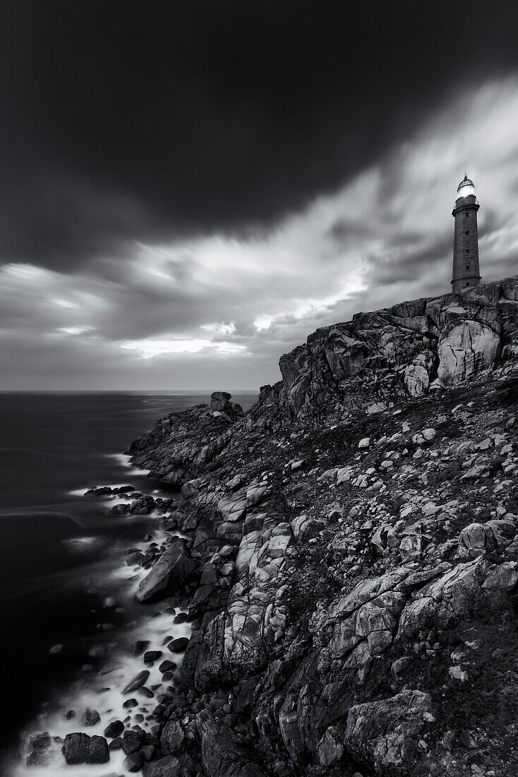 Black-and-white Photo of the Cabo Vilan lighthouse at the top of the Cape at Costa da Morte along the rugged coastline in northern Spain, Galicia, Spain