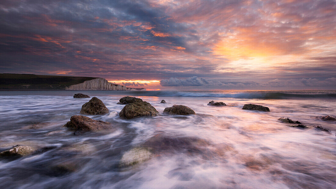 Spektakulärer Sonnenaufgang über der Bucht von Cuckmere in der südenglischen Grafschaft Sussex mit den eindrucksvollen Kreideklippen der Seven Sisters im Hintergrund, England, Großbritannien