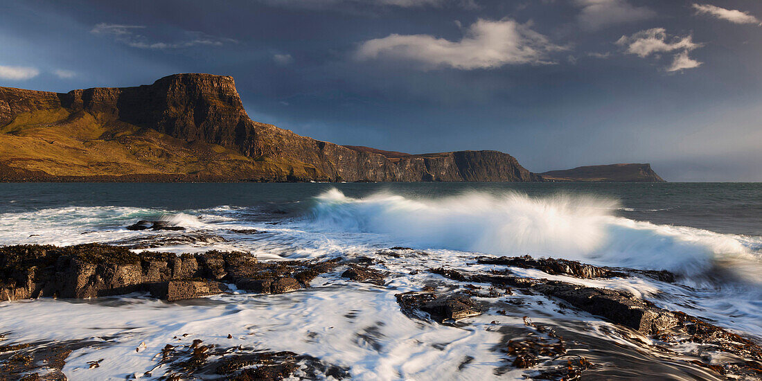 Incoming surf with view to the impressive cliffs of Waterstein head at the western end of the Isle of Skye, Scotland, United Kingdom