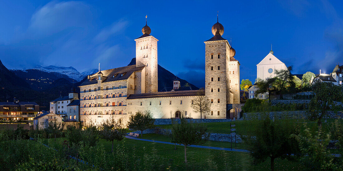 Abenddämmerung über dem Stockalperschloss in Brig mit verschneiten Bergen im Hintergrund, Wallis, Schweiz